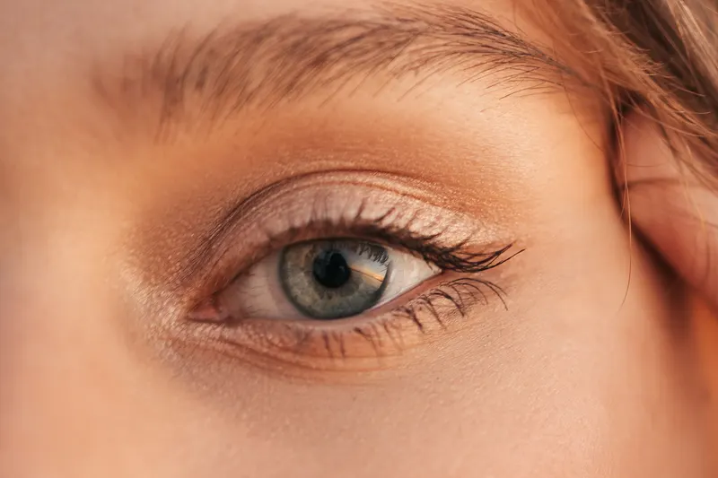 Blue-gray eye with peach and terracotta eyeshadow blended across the lid