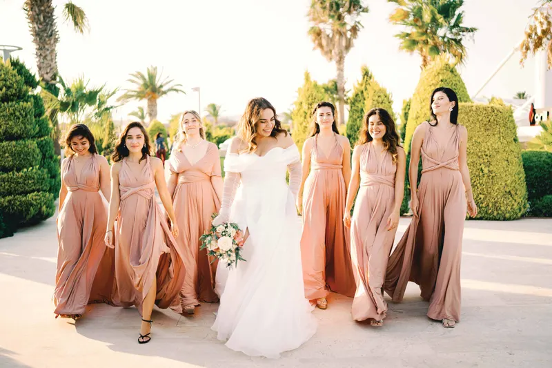 Bride walking with bridesmaids in blush dresses, each with her own hairstyle