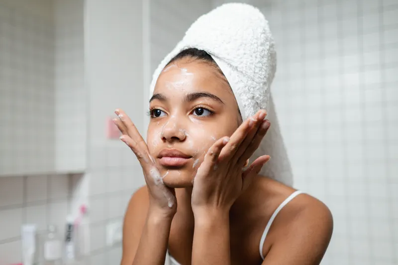 A young woman gently washes her face with her fingertips