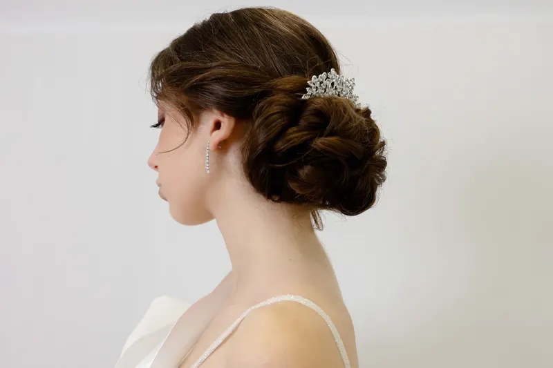 Side profile of a bride with a low, sculpted updo and a sparkling hair piece