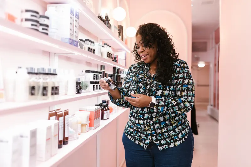 A woman reads the label of a skincare product in a beauty store