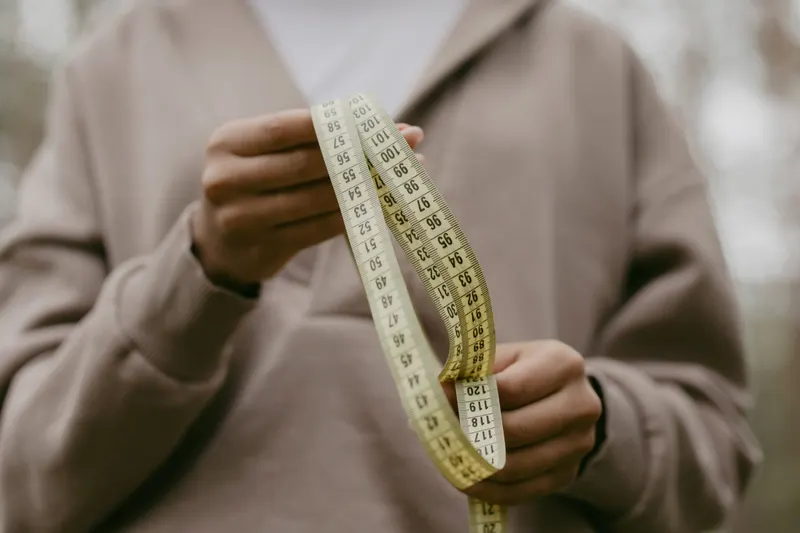 Hands hold a soft measuring tape ready to measure