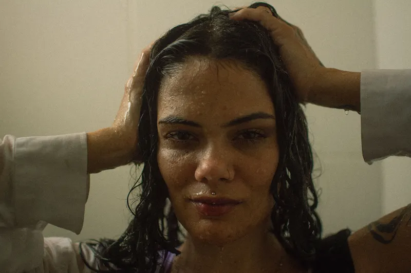 A woman works product through her wet hair in the shower