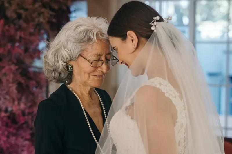Mother of the bride with glasses and a pearl necklace, smiling with the bride