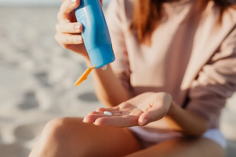 Sunscreen being squeezed into a hand outdoors