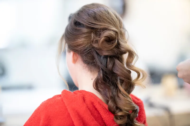 Long, soft bridal curls swept to one side, seen from behind