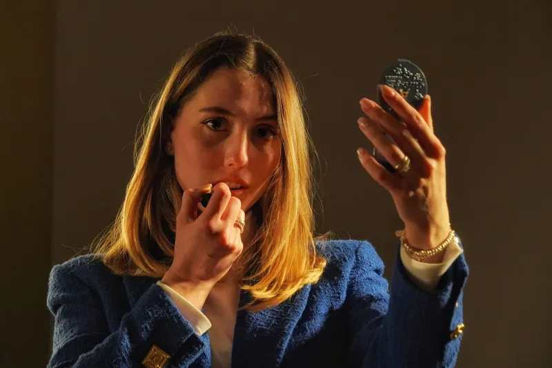 Woman touching up her lipstick with a compact mirror