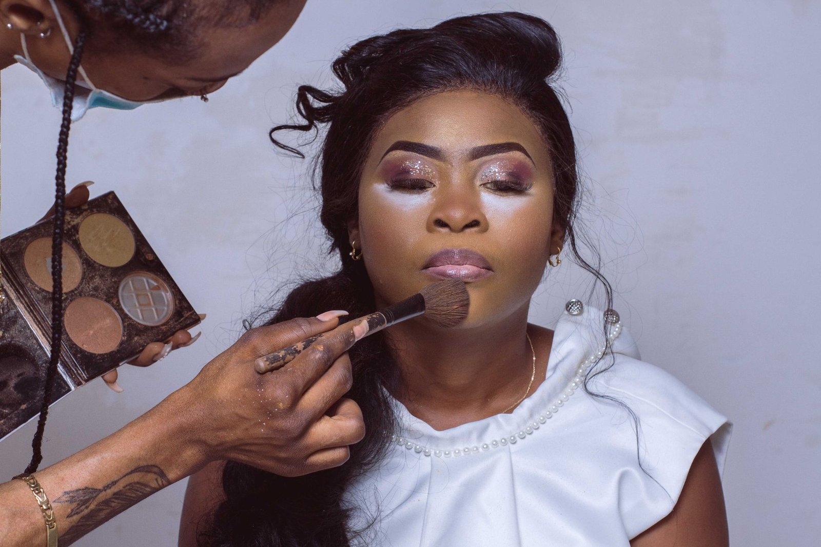 A makeup artist blends soft glam makeup around a bride's eyes.