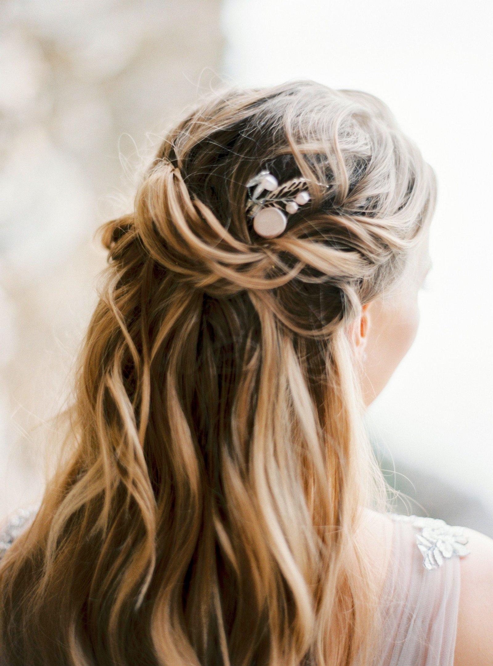 A bride wears a half-up wedding hairstyle for medium length hair, blending an updo and down style.