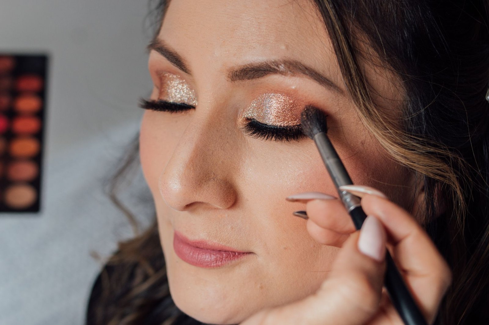 A makeup artist carefully layers full glam makeup for a bride's photos.