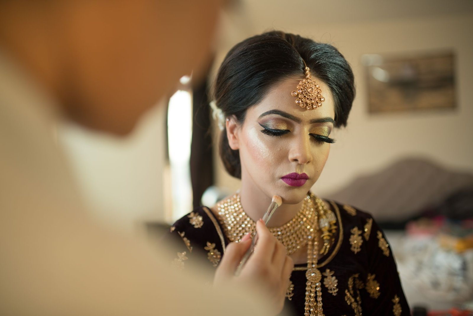 A makeup artist builds rich, defined eye color for South Asian wedding makeup.