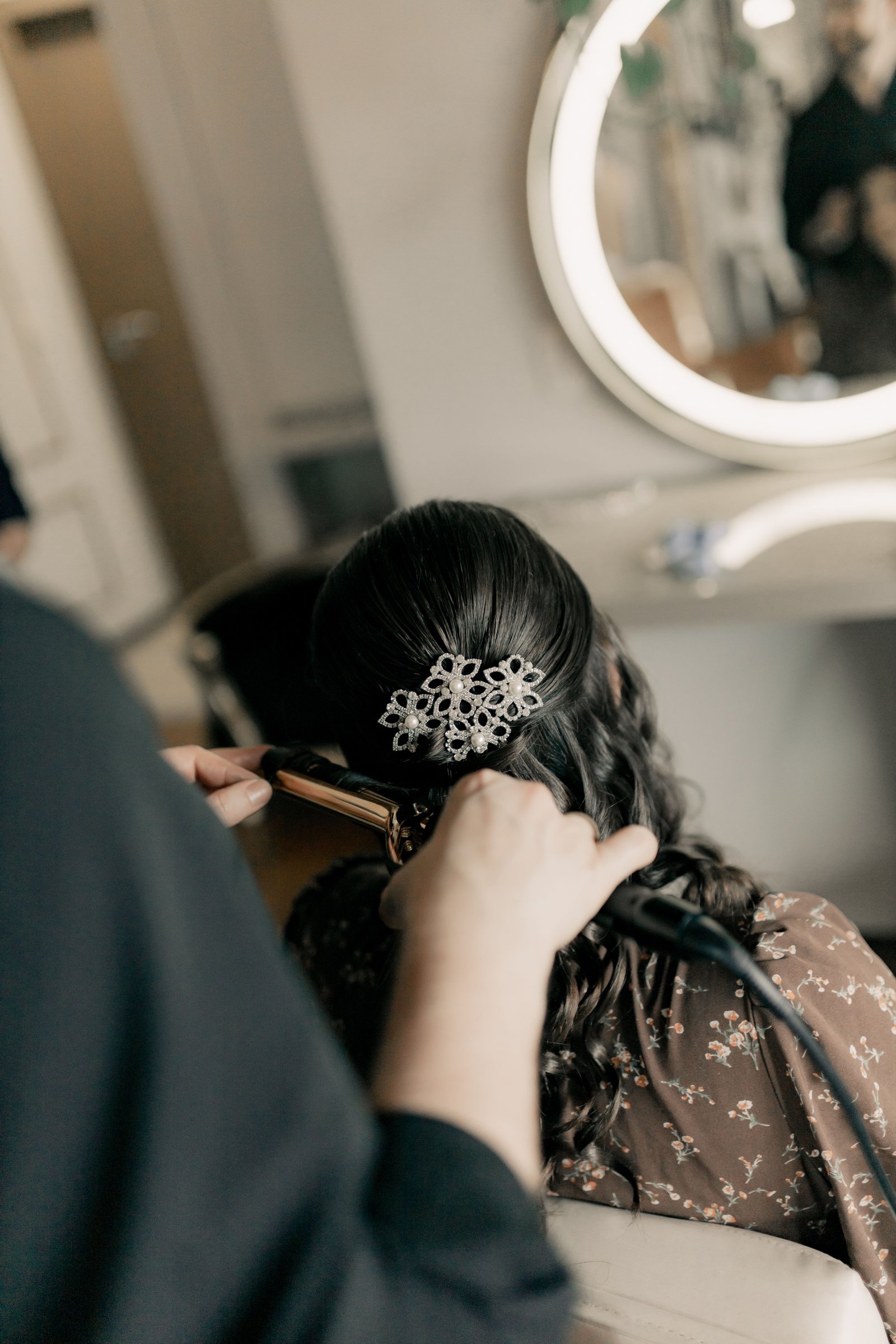 A stylist curls bridal hair with a curling iron, demonstrating technique behind lasting wedding curls.