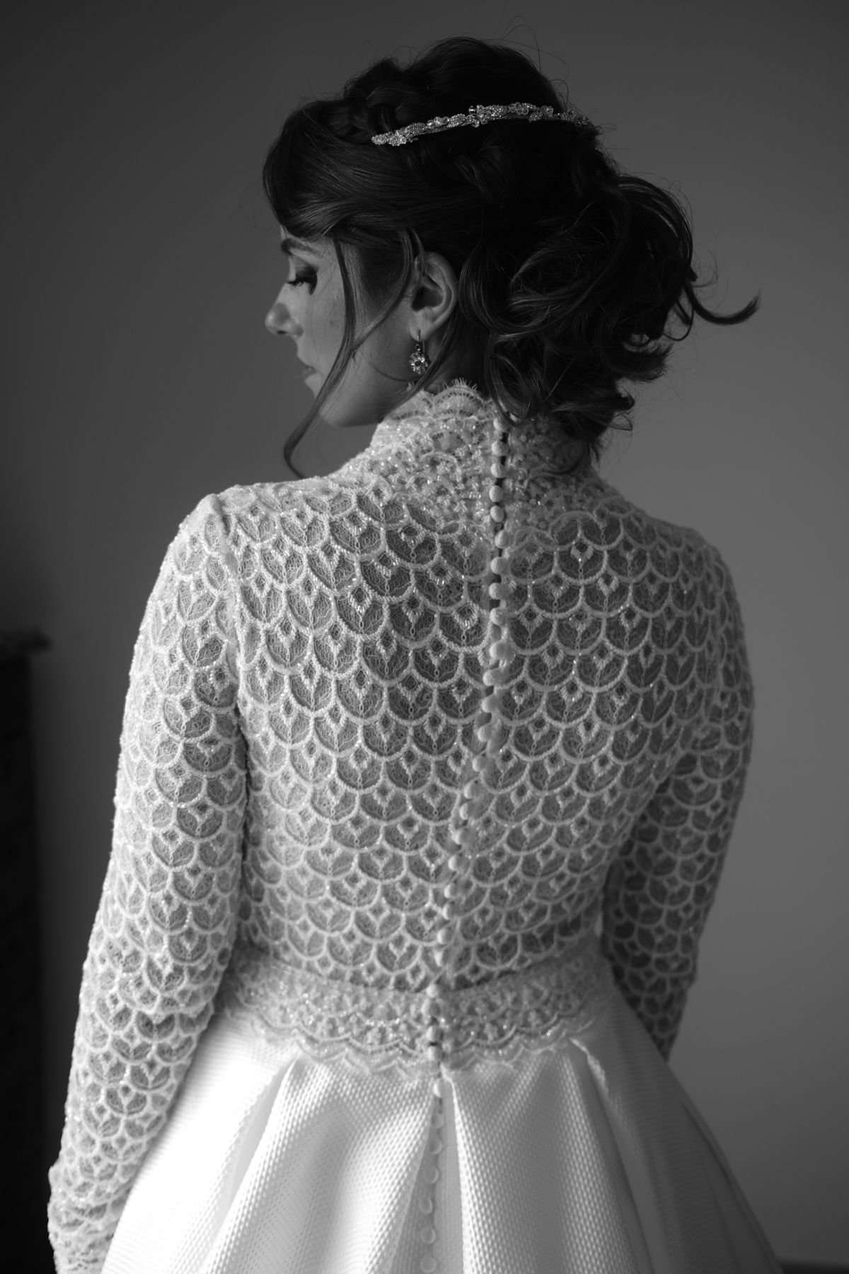 A mother of the bride wearing a formal chignon updo paired with an elegant headpiece.
