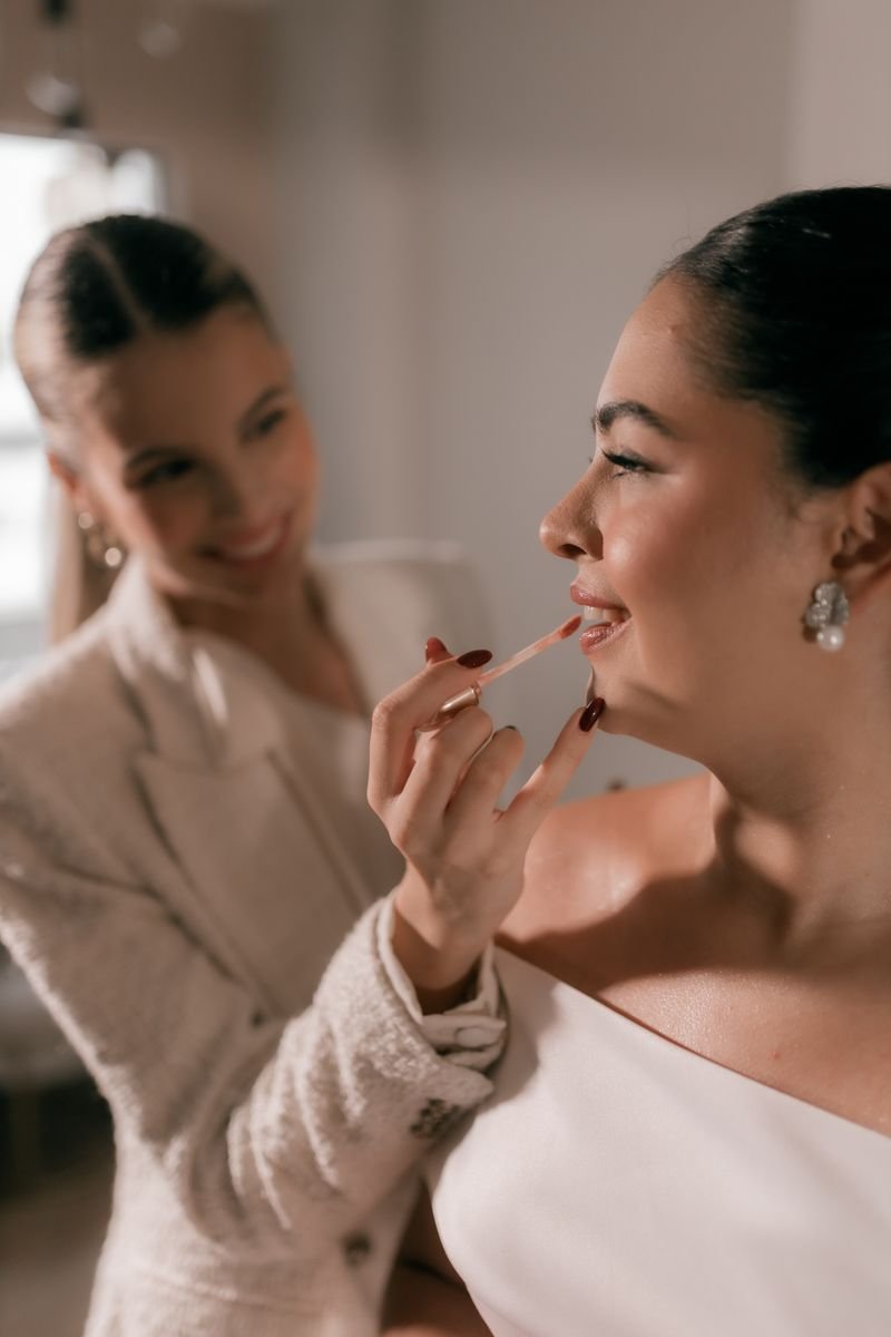 A bride laughing while touching up her lipstick from her bridal cosmetics kit.