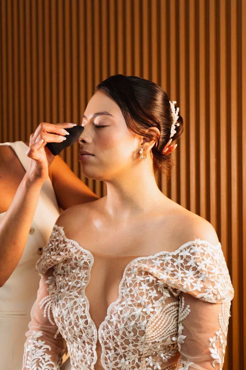 A bride receives a touch up of airbrush makeup before her wedding ceremony.