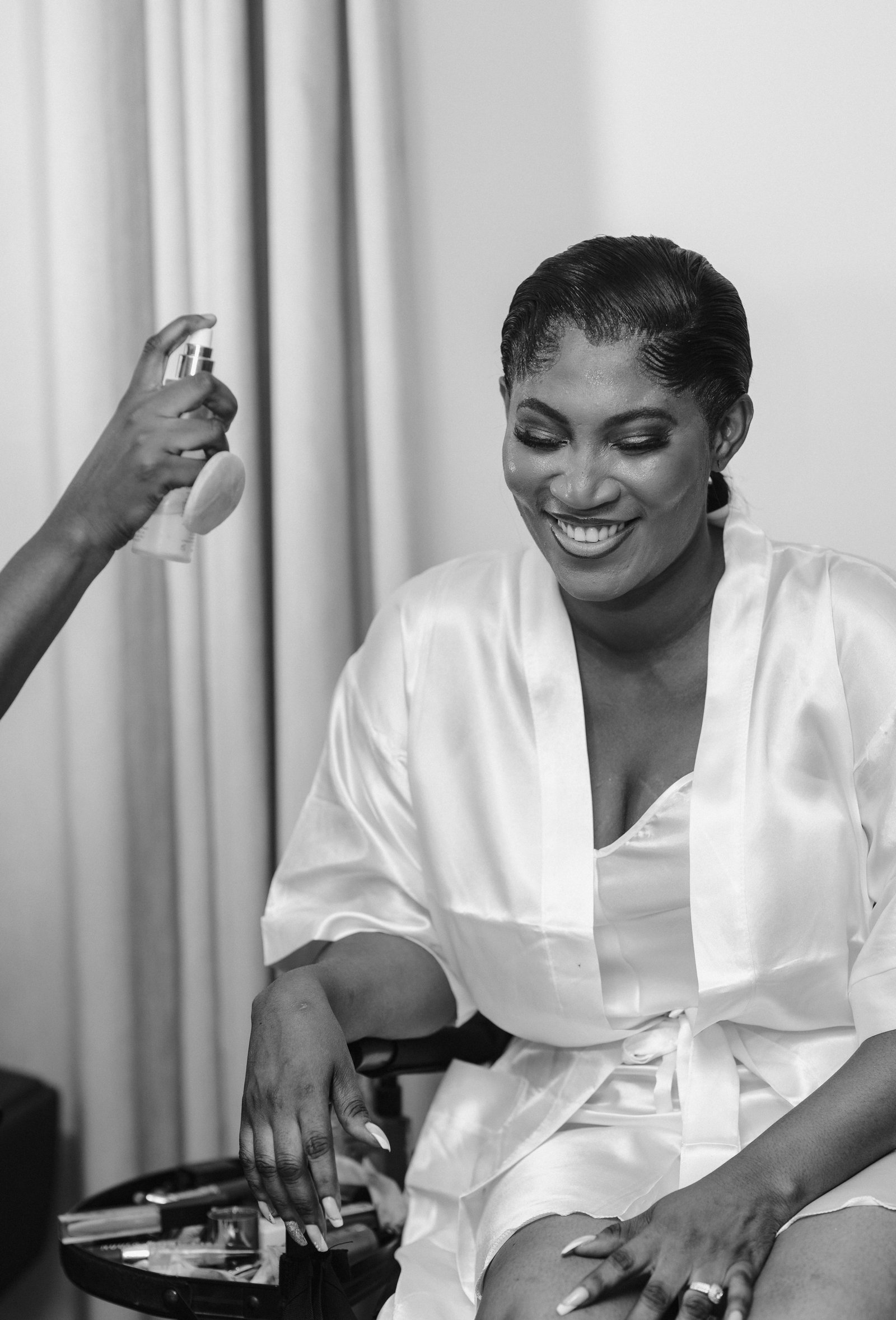A professional makeup artist demonstrates part of what affects wedding makeup cost, applying airbrush foundation to a bride's face.