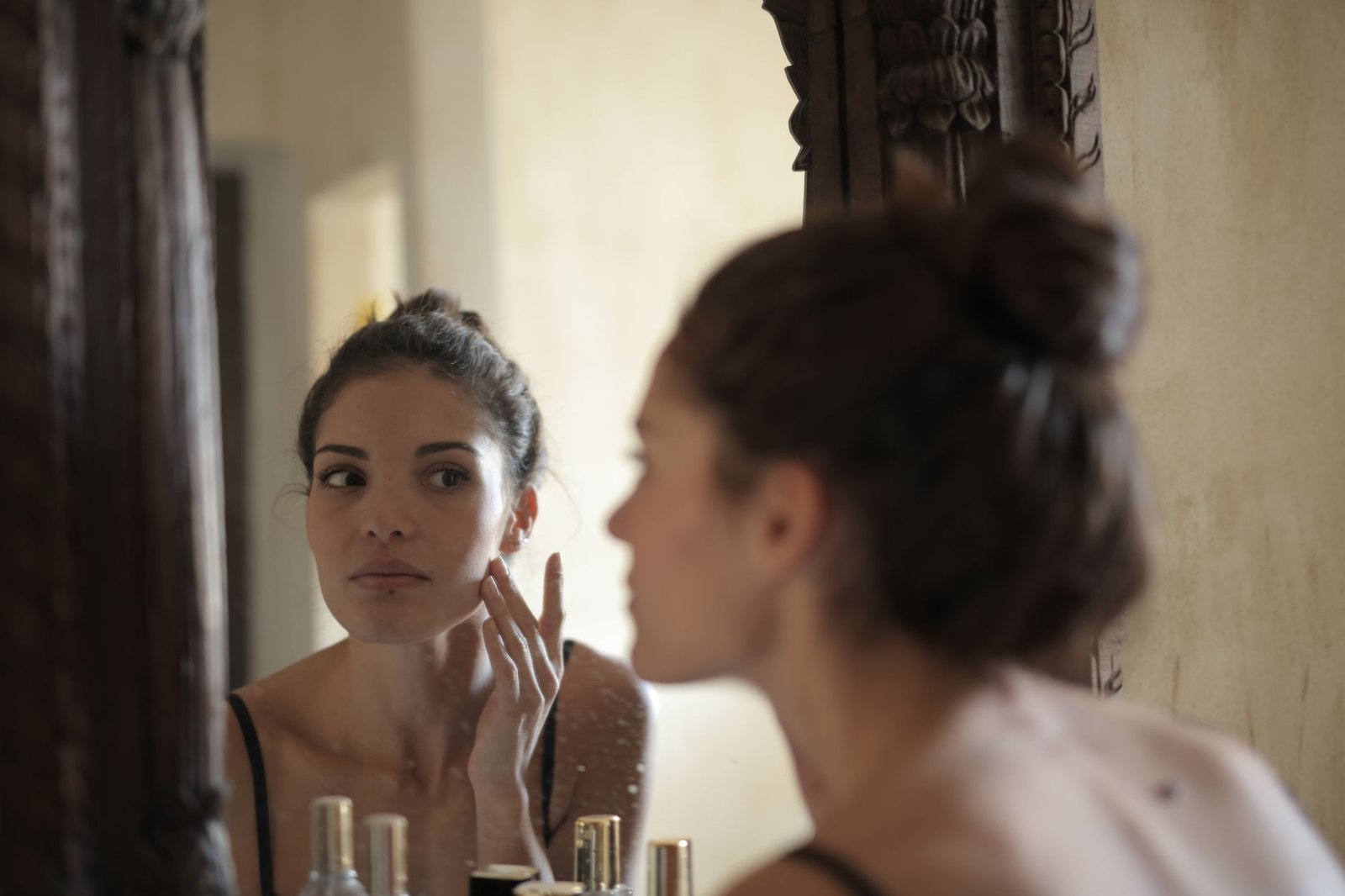 A woman gently applies a skincare product as part of her bridal skincare routine.