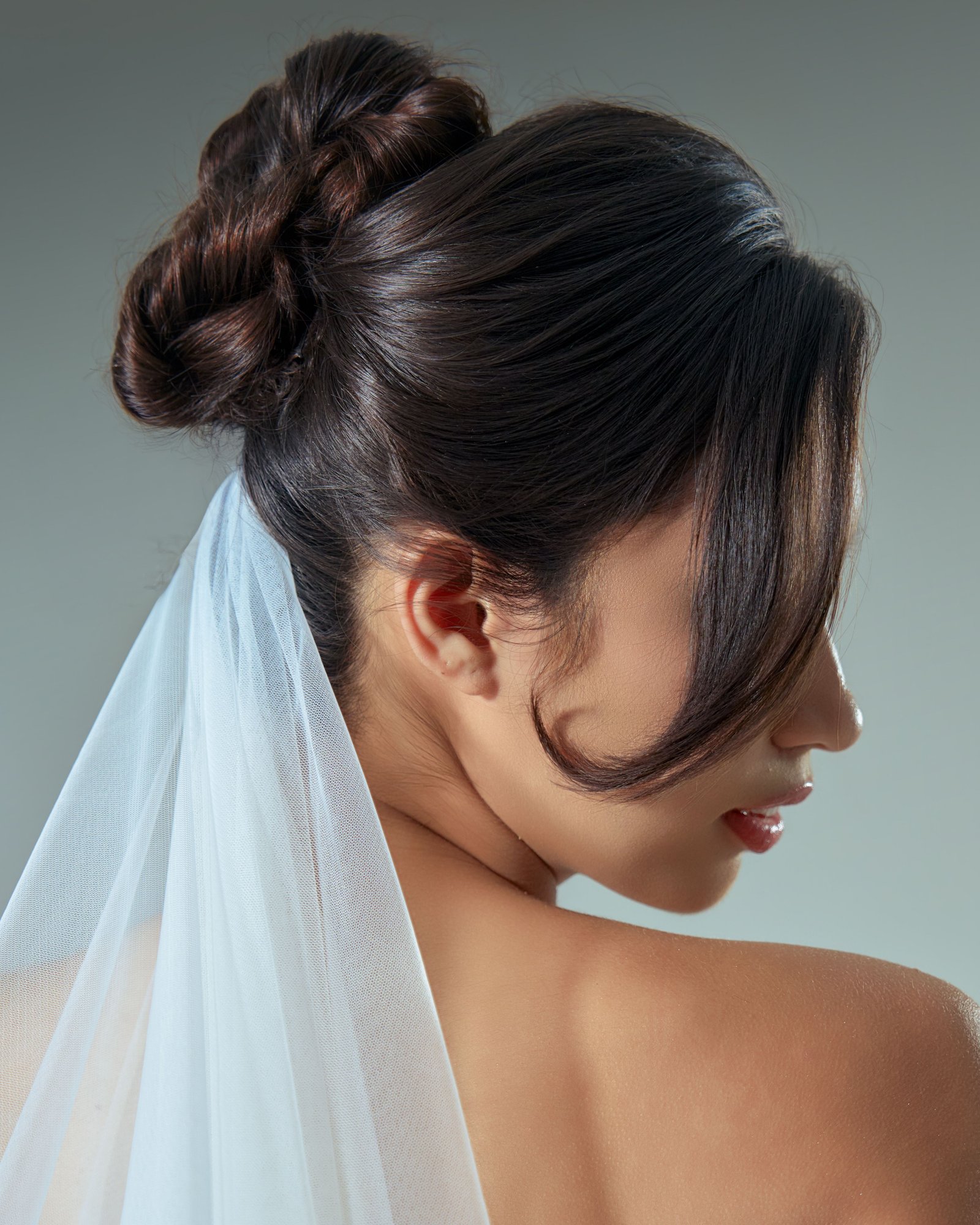 A bride wears a textured high bun, a romantic bridal updo style with soft volume.