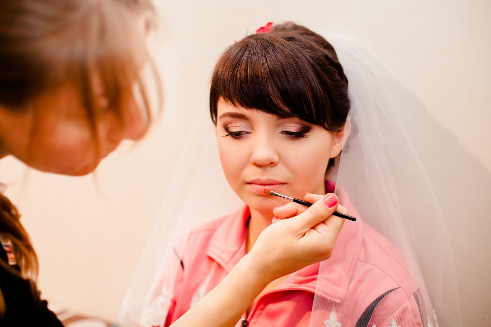 A makeup artist applies Dior Backstage Rosy Glow blush stick to a bride's cheek.