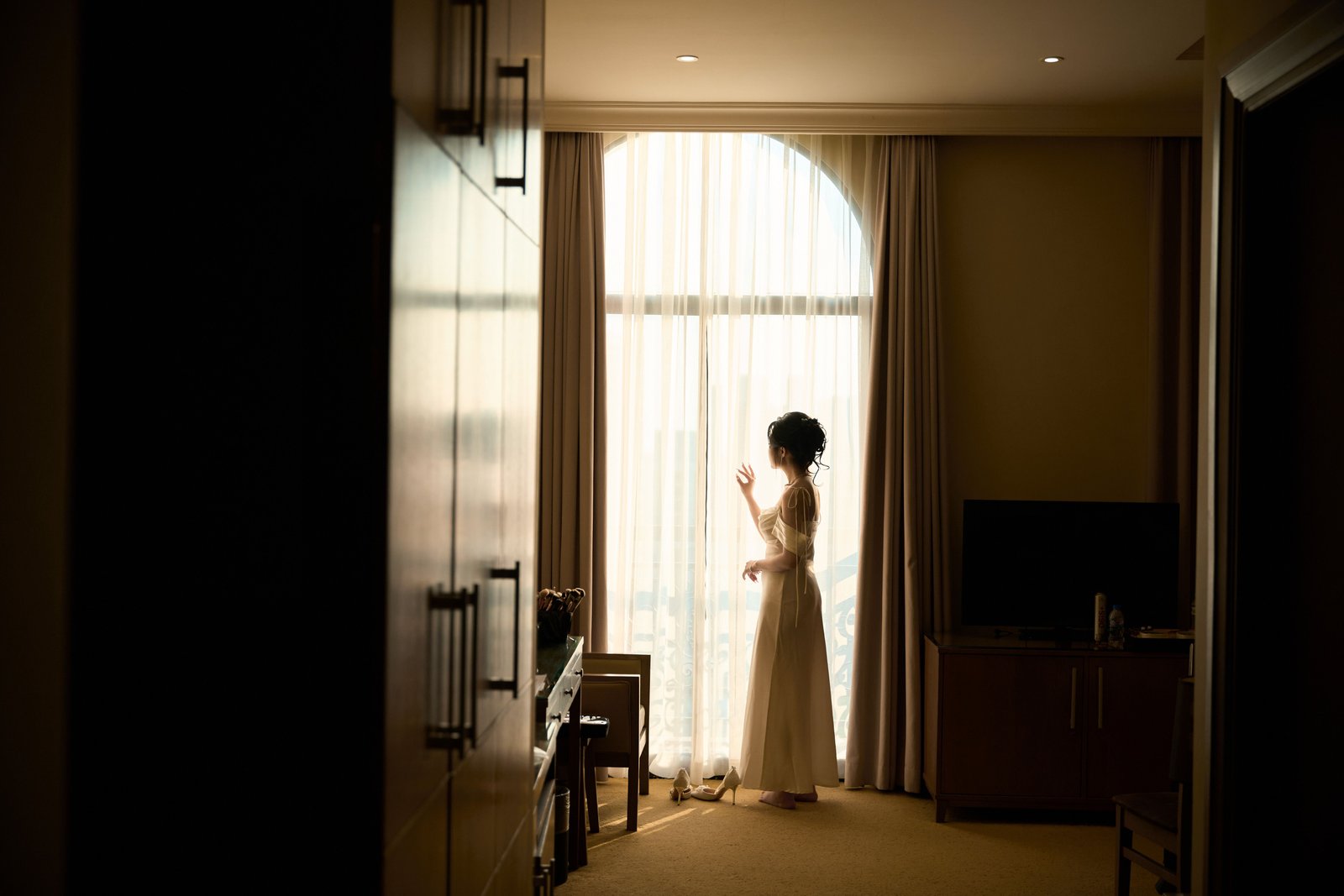 A bride gets ready in a hotel room, an example of on-location wedding hair and makeup brought directly to her space.