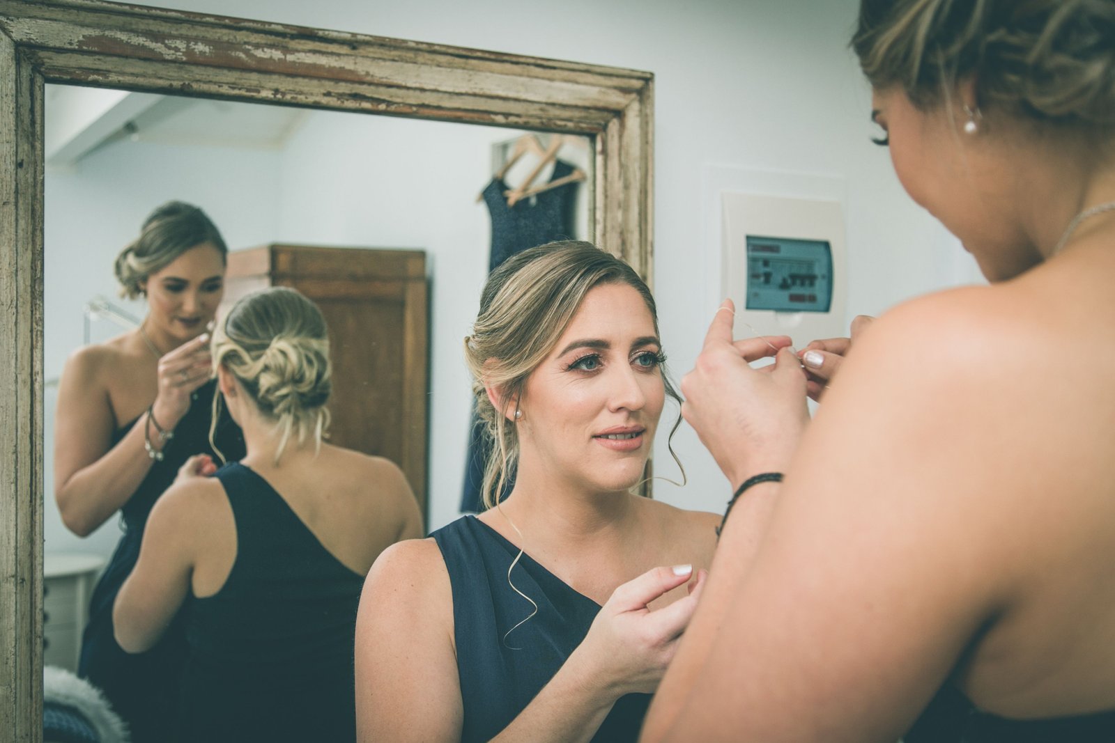 Multiple bridesmaids having their bridesmaid hairstyles finished together in matching soft updos before the ceremony.