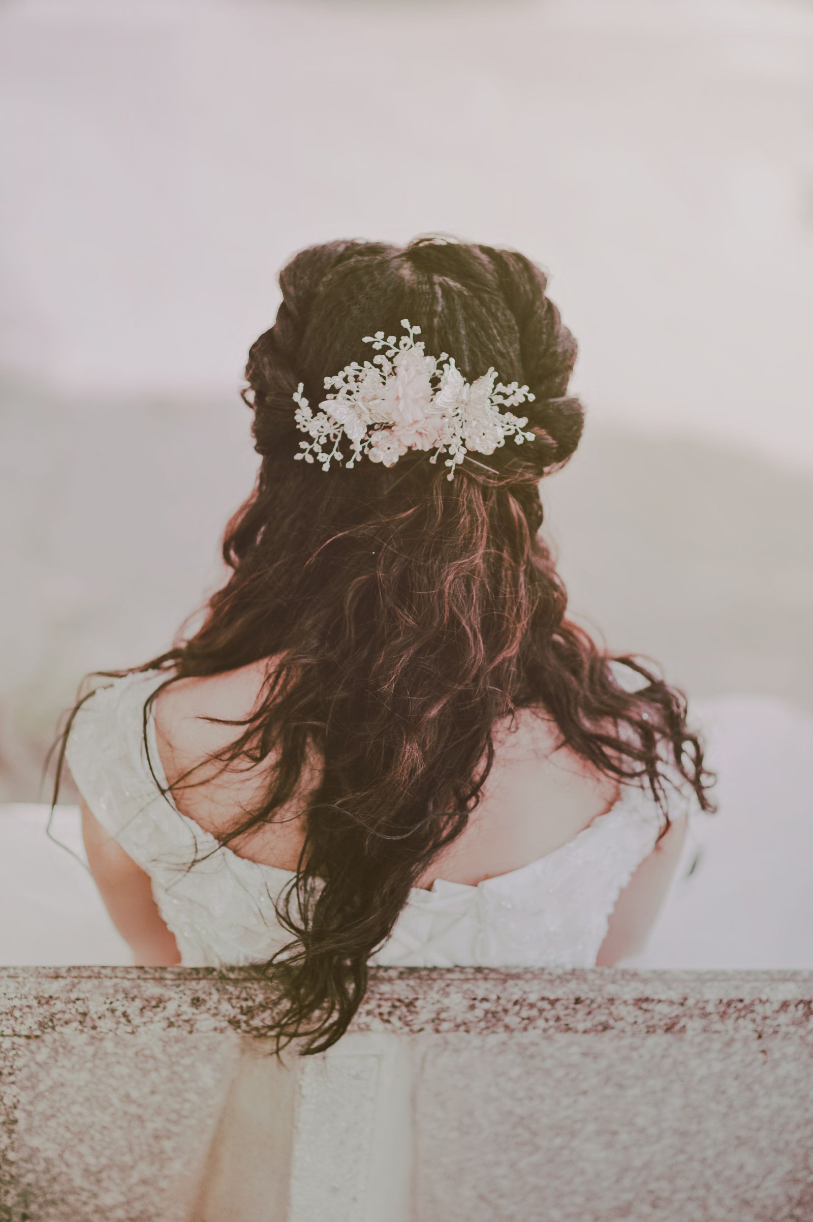 A bride with long hair wears cascading curls, one of the most popular wedding hairstyles for long hair.