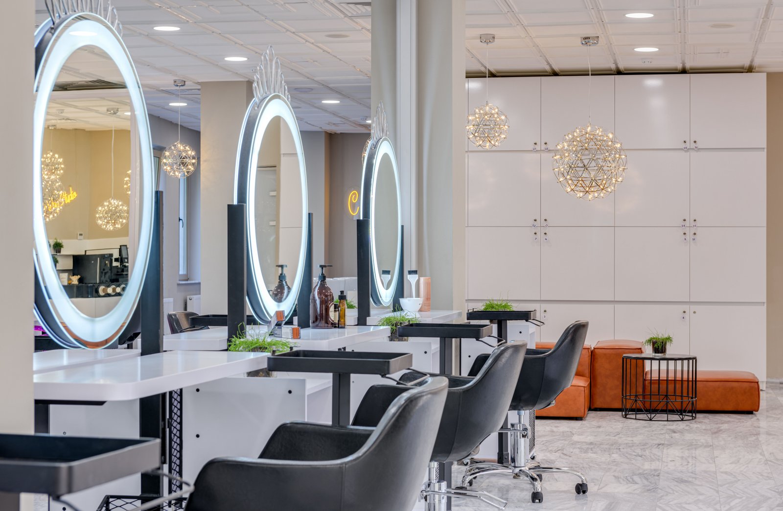 A row of salon chairs and mirrors, one setting brides consider for on-location wedding hair and makeup versus a salon visit.