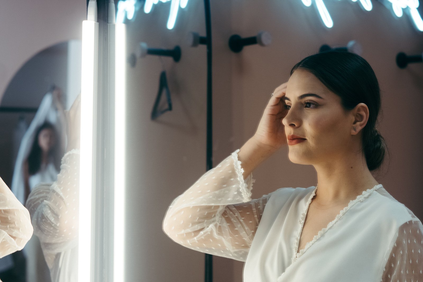 A bride admires her finished look in the mirror after working with a professional bridal makeup artist.