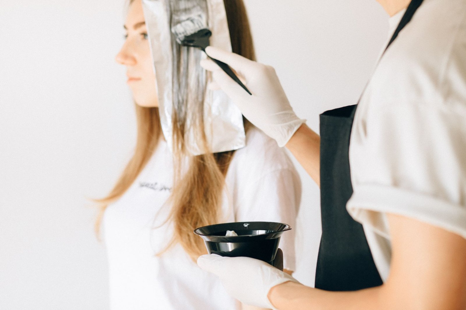 A colorist works on a client's hair color appointment before a wedding.