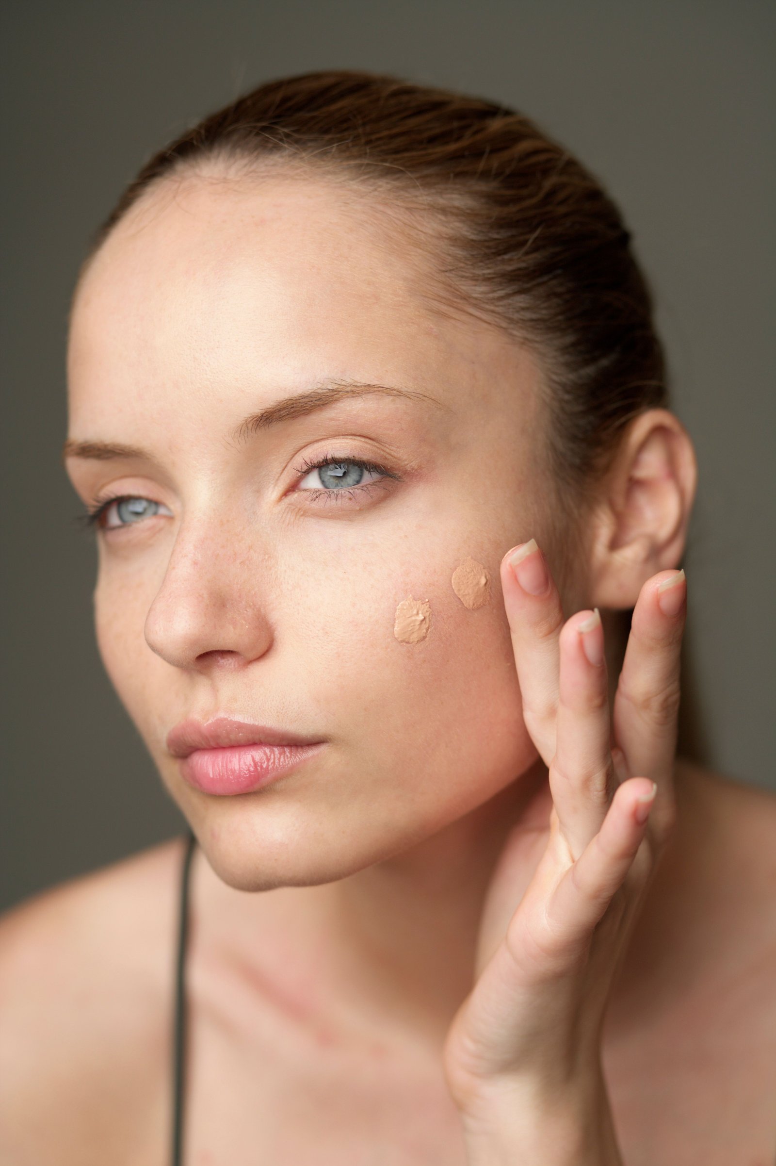 Makeup base cream being smoothed onto skin before foundation
