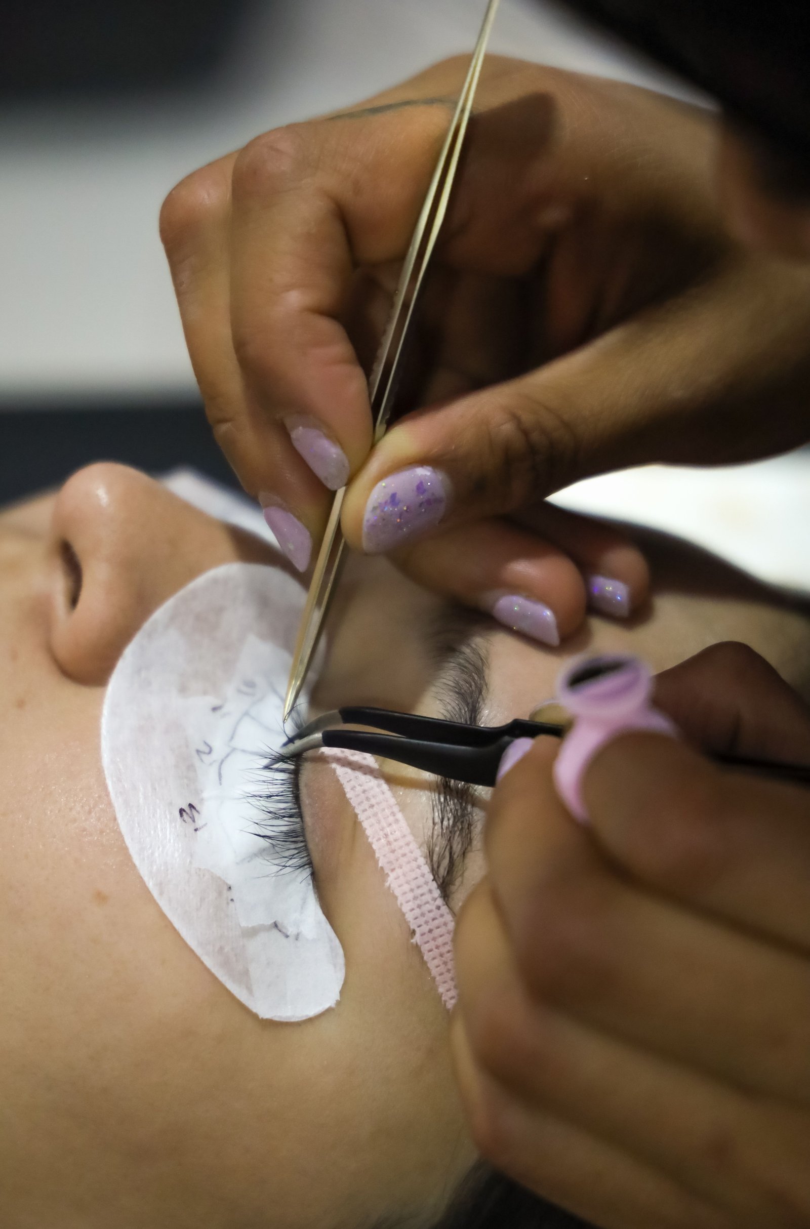 Technician placing individual Ardell lash clusters with tweezers