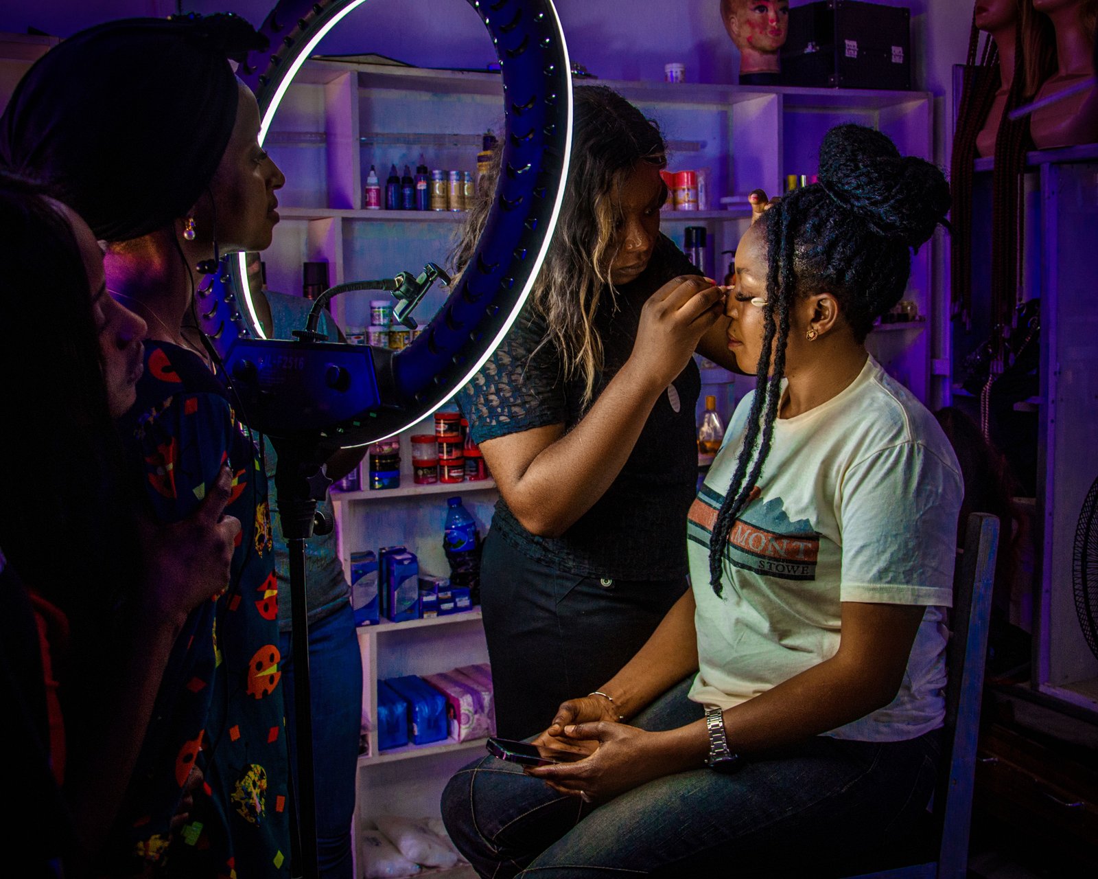 Makeup artist applying cosmetics to a client under studio lighting
