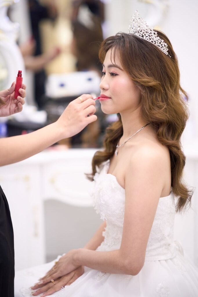 Makeup artist touching up a bride's lipstick after setting her look with make up setting spray