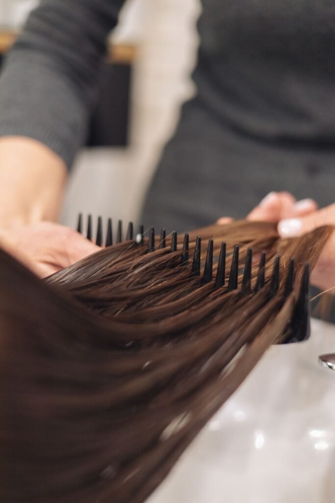 Stylist combing through a client's wet hair during a salon hair bonding treatment