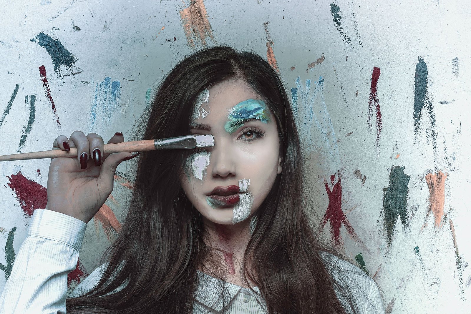 Artist applying creative white face paint design during a styled photoshoot