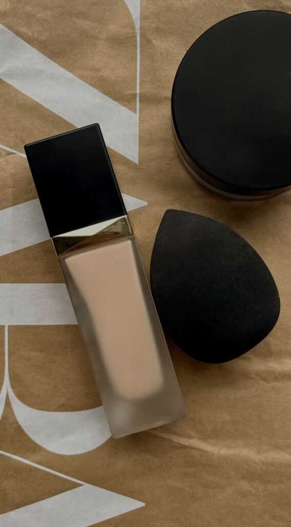 Several foundation makeup bottles in different shades beside blending sponges and brushes