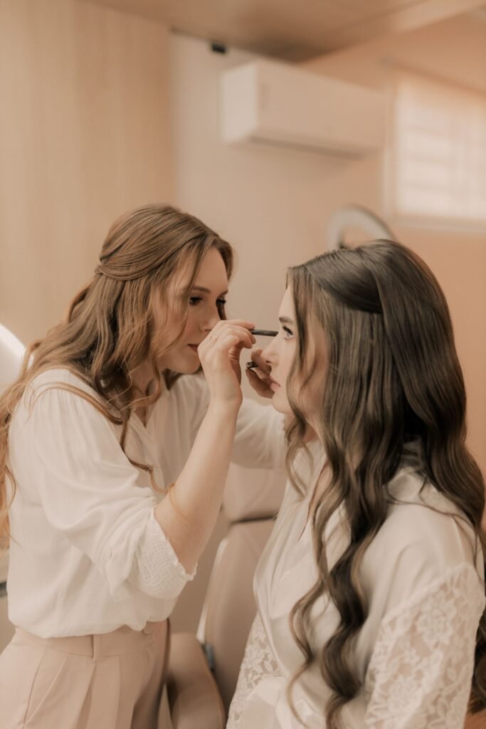 Makeup artist applying eyeliner around permanent eyelash extensions on a bride