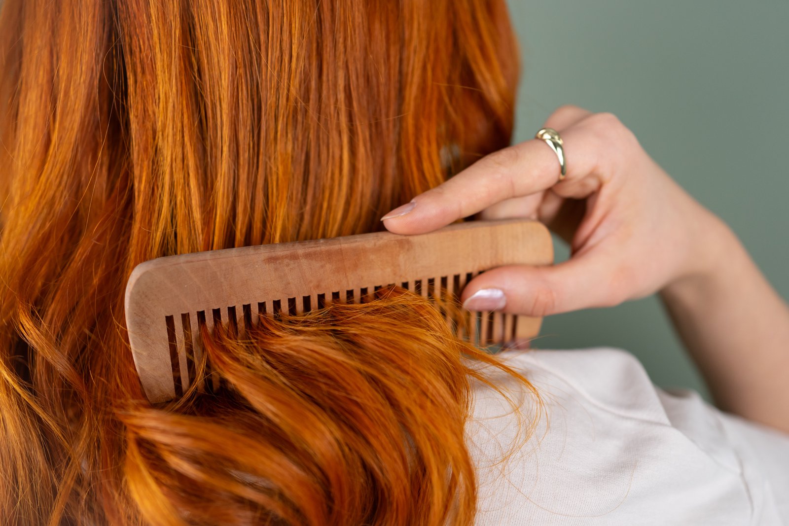 Close-up of a woman combing her long, shiny hair with a wooden comb