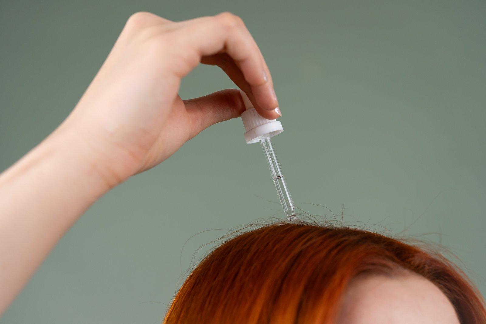 Close-up of hair serum being applied by hand before styling