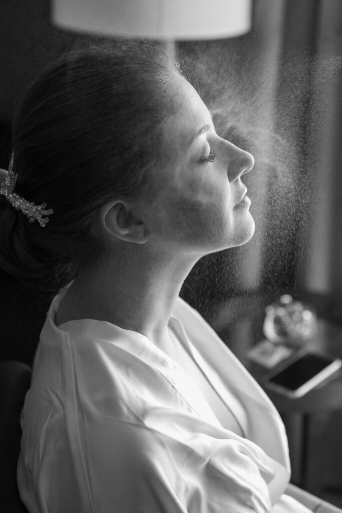 Makeup artist finishing a bride's look with the best setting spray for makeup for a long wedding day
