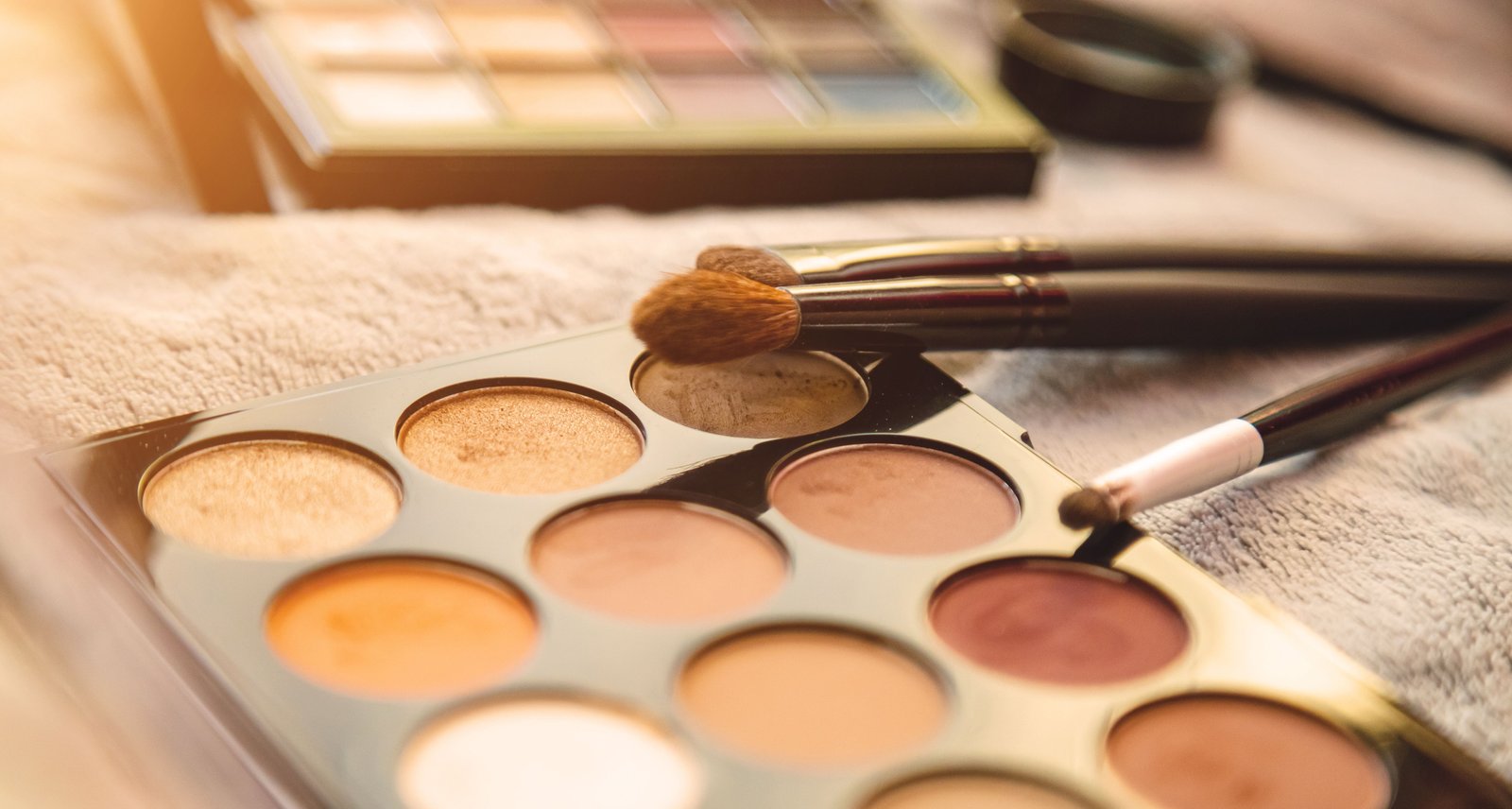 Neutral eyeshadow palette and blending brushes laid out for a trial application