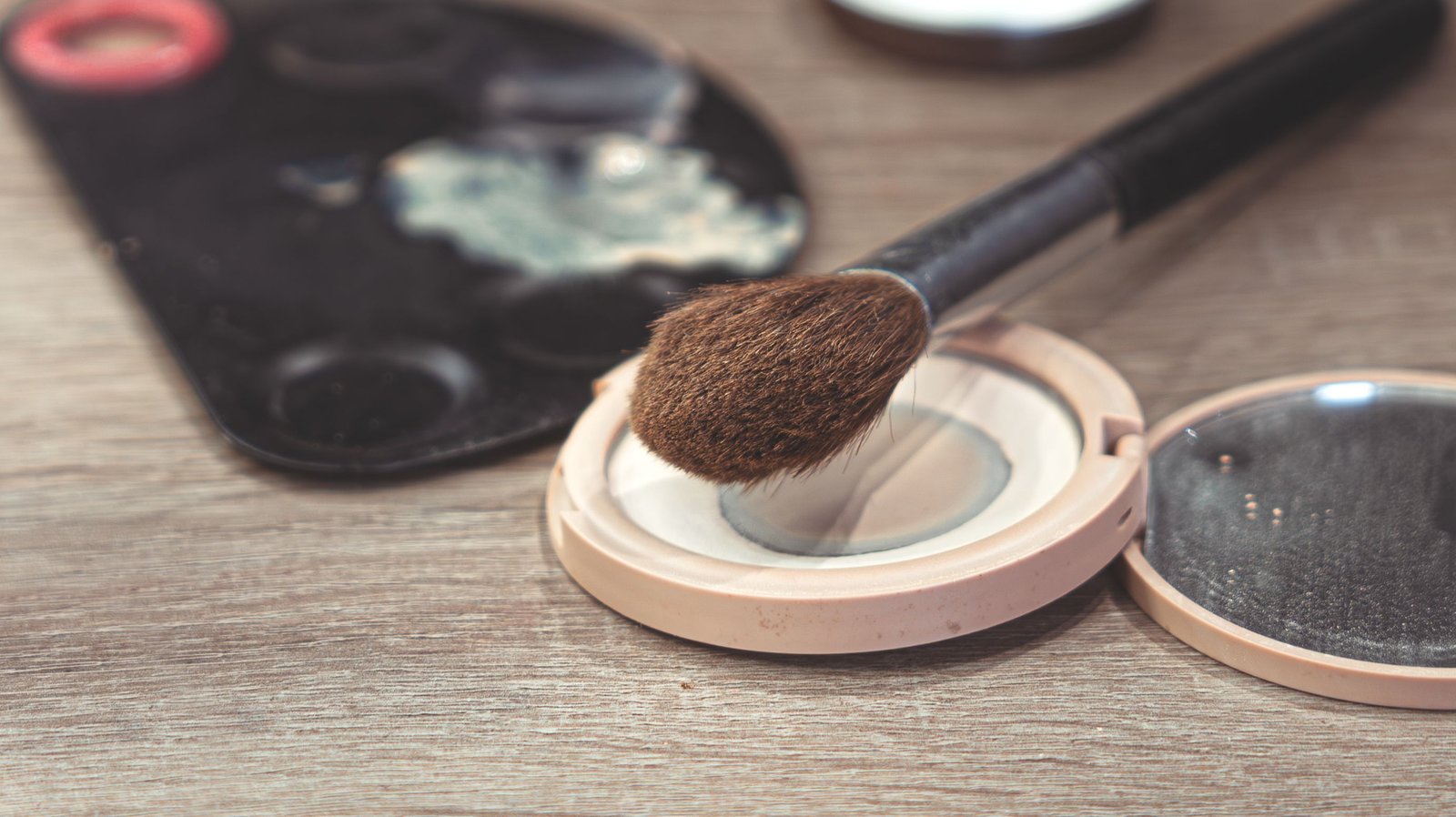 Makeup brush resting on an open setting powder compact