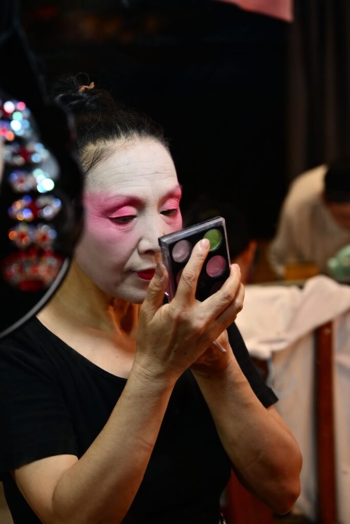 Performer applying Mehron foundation greasepaint style theatrical makeup backstage