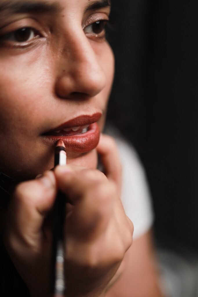 Close up of a woman lining her lips before applying a warm brown lipstick