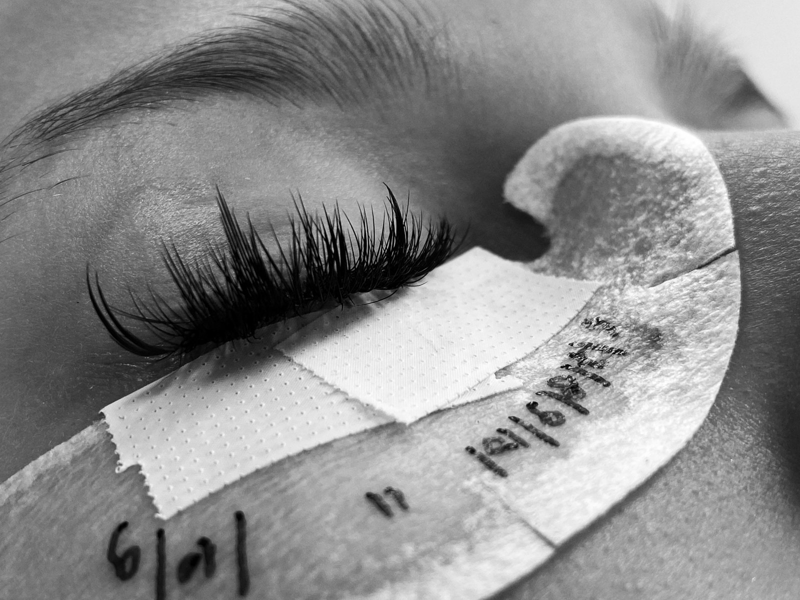 Close-up of a lash artist hand-fanning volume eyelash extensions during application