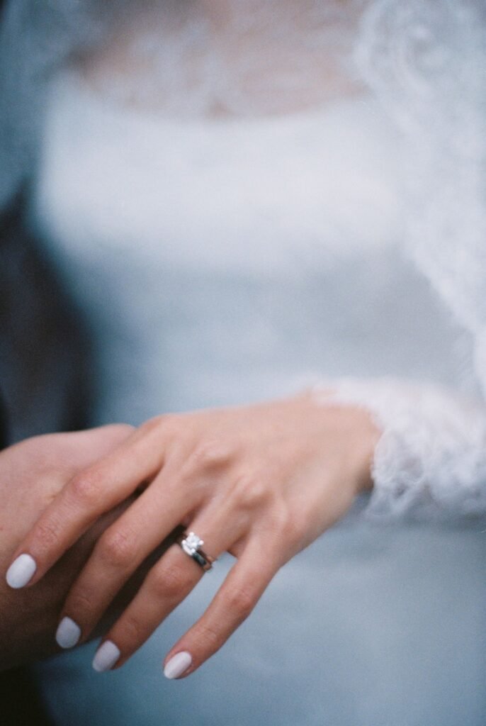 Bride's hand with a wedding ring and a neat manicure, where Kiss Pink Gel nail glue press ons need to look flawless