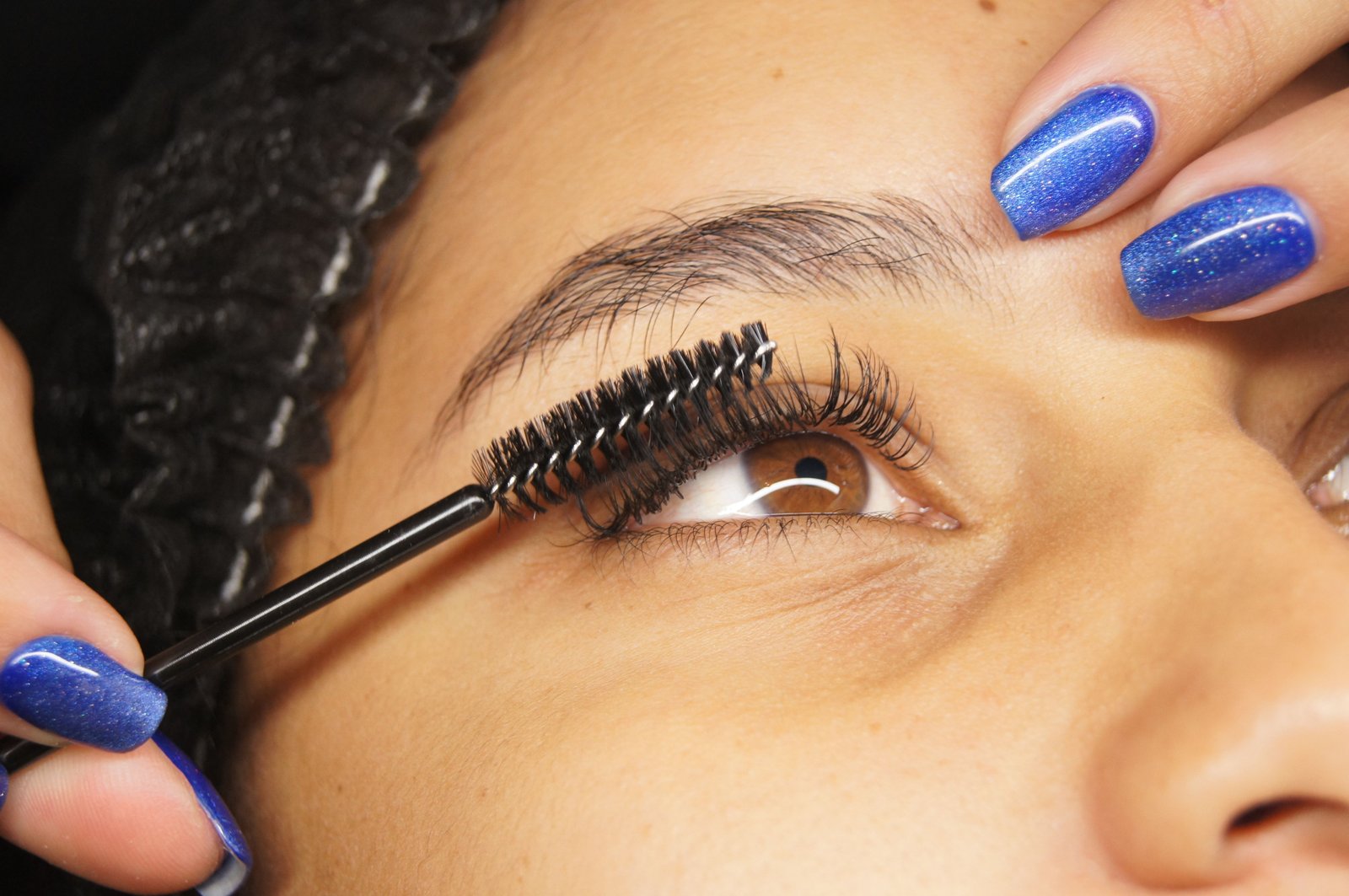 Close-up of a classic eyelash extension being applied to a single natural lash