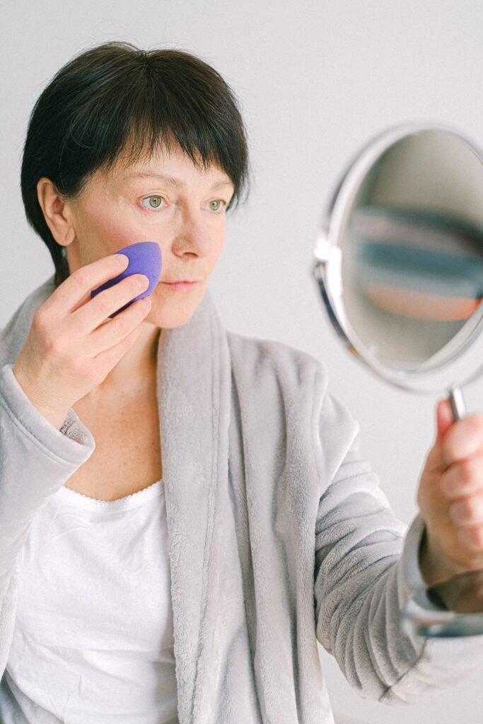 Woman pressing makeup into her skin with a sponge, a step that helps make up setting spray last
