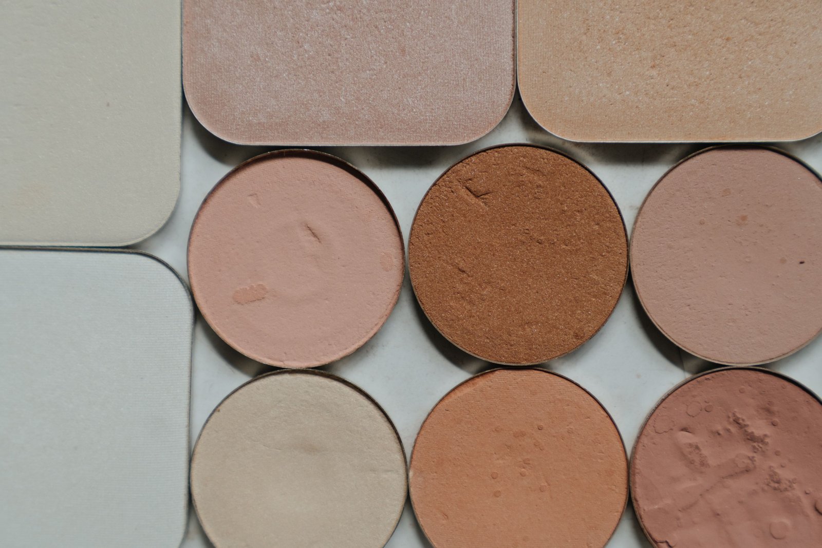 Flat lay of warm nude makeup shades used to build a soft matte bridal look