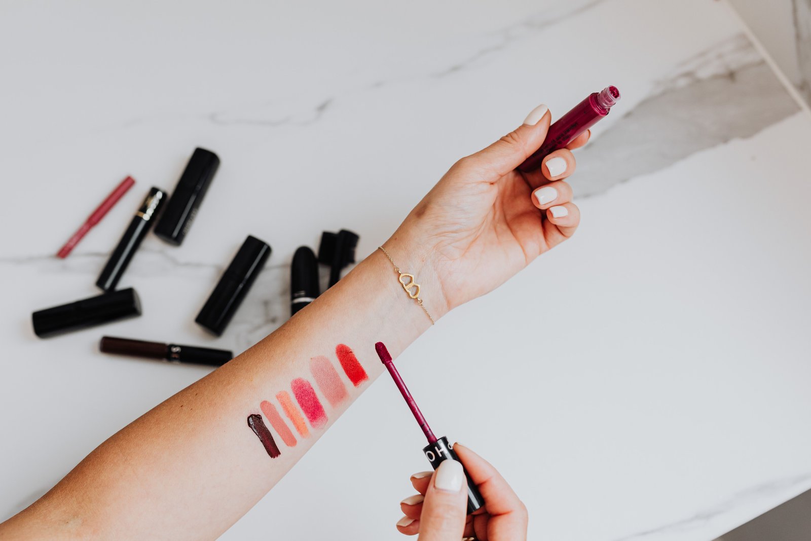 Testing multiple lipstick shades against skin before deciding on one